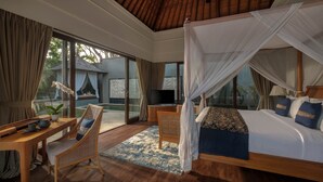 A bedroom with a canopy bed, a television, a desk with a chair, and a view of the outside. - The Shanti Residence By Nakula (Nusa Dua)