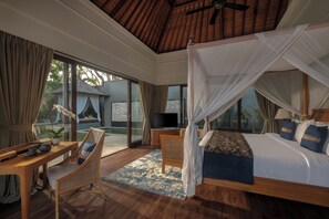 A bedroom with a canopy bed, a television, a desk with a chair, and a view of the outdoors. - The Shanti Residence By Nakula (Nusa Dua)