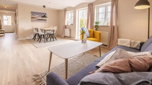 A spacious living area with a dining table, sofa, and a view of the outdoors. - 4 Star Holiday Home in Hjorring (Hjørring)