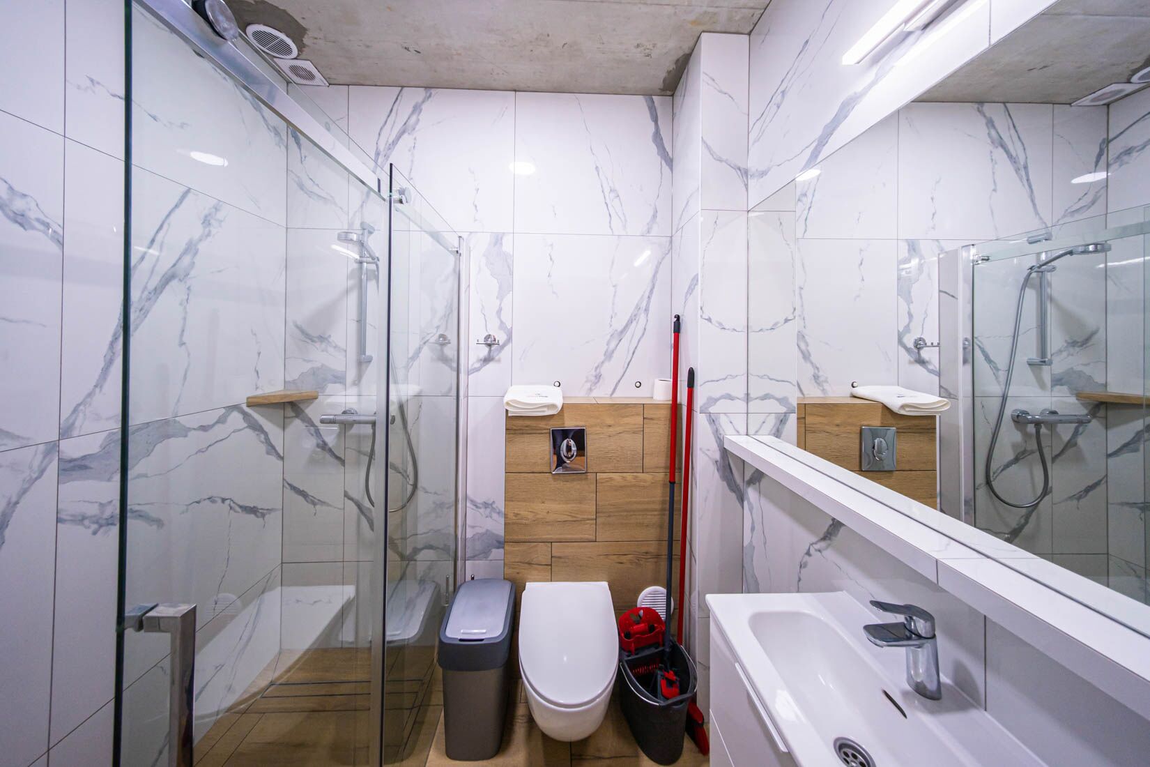 A modern bathroom with a glass shower enclosure, a white toilet, and a bathtub.