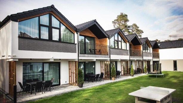 A modern multi-story residential building with large windows, balconies, and a well-maintained lawn. - Gold Time (Niechorze)