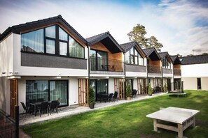 Un moderno edificio residenziale a più piani con ampie finestre, balconi e un prato curato.