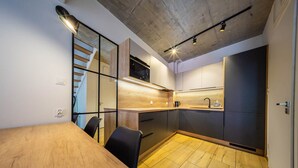 A modern kitchen with a wooden dining table, black chairs, and a built-in stove. - Gold Time (Niechorze)
