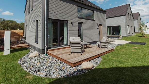 A modern two-story house with a deck, large windows, and a well-maintained lawn. - 4 Star Holiday Home in Sagad (Sagard)