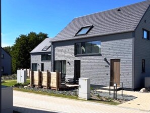 Een modern herenhuis met twee verdiepingen, een schuin dak, grote ramen en een zichtbare schotelantenne.