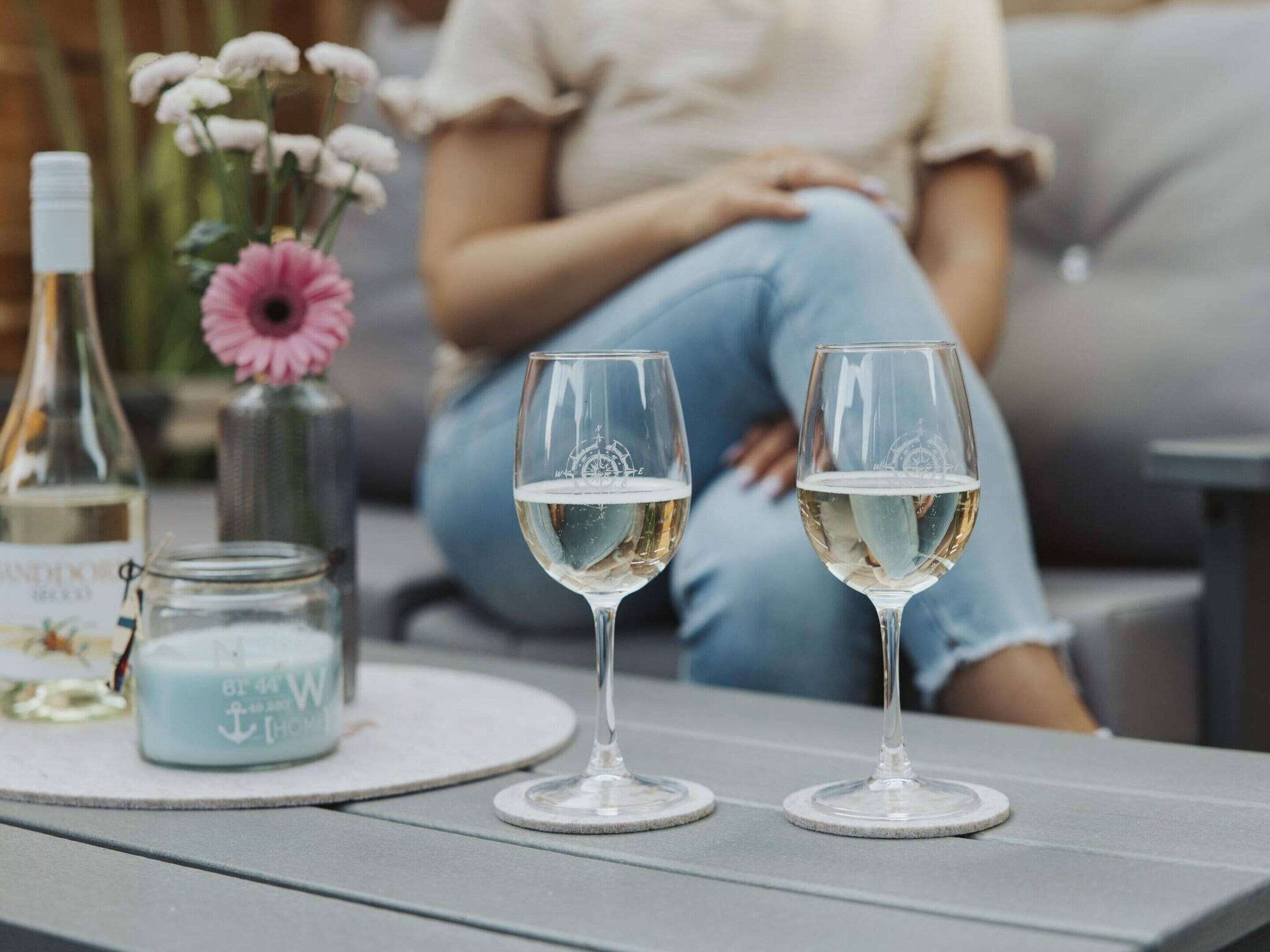 Zwei Weingläser auf einem Tisch mit einer Flasche und einem Glas.
