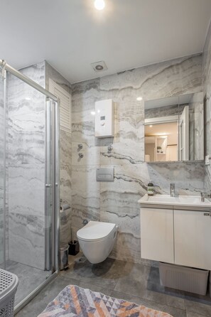 Ein Badezimmer mit Dusche, Toilette, Waschbecken und Marmorwänden.