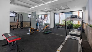 A modern gym with cardio machines, free weights, and a bench.