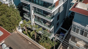 A multi-story building with balconies, a flat roof, and satellite dishes.