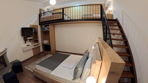 A loft-style bedroom with a wooden bed, a curved staircase, and a TV on a shelf. - salillari guest house (Vërtop)