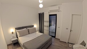 A modern bedroom with a bed, bedside lamps, a small table, and a chair. - salillari guest house (Vërtop)