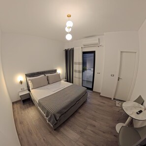 Un dormitorio moderno con cama, lámparas de noche, una mesita y una silla.