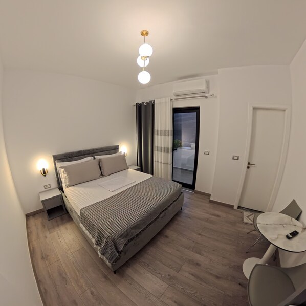 A modern bedroom with a bed, bedside lamps, a small table, and a chair. - salillari guest house (Vërtop)
