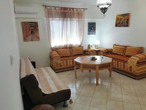 A living room with a sofa set, a coffee table, a bench, and a chandelier. - L'Oranger | Cosy air-conditioned apartment 3 min from the Souk, near Agadir beach (Agadir)