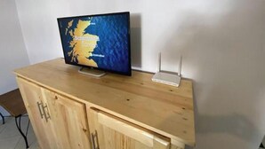 Een televisie op een houten kast met een kaart, een witte router en een metalen standaard.
