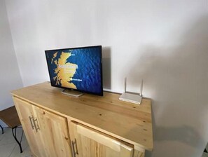 A television on a wooden cabinet with a map display, a white router, and a metal stand. - Charming Le Palmier apartment - Close to the beach, Souk El Had and the town center (Agadir)