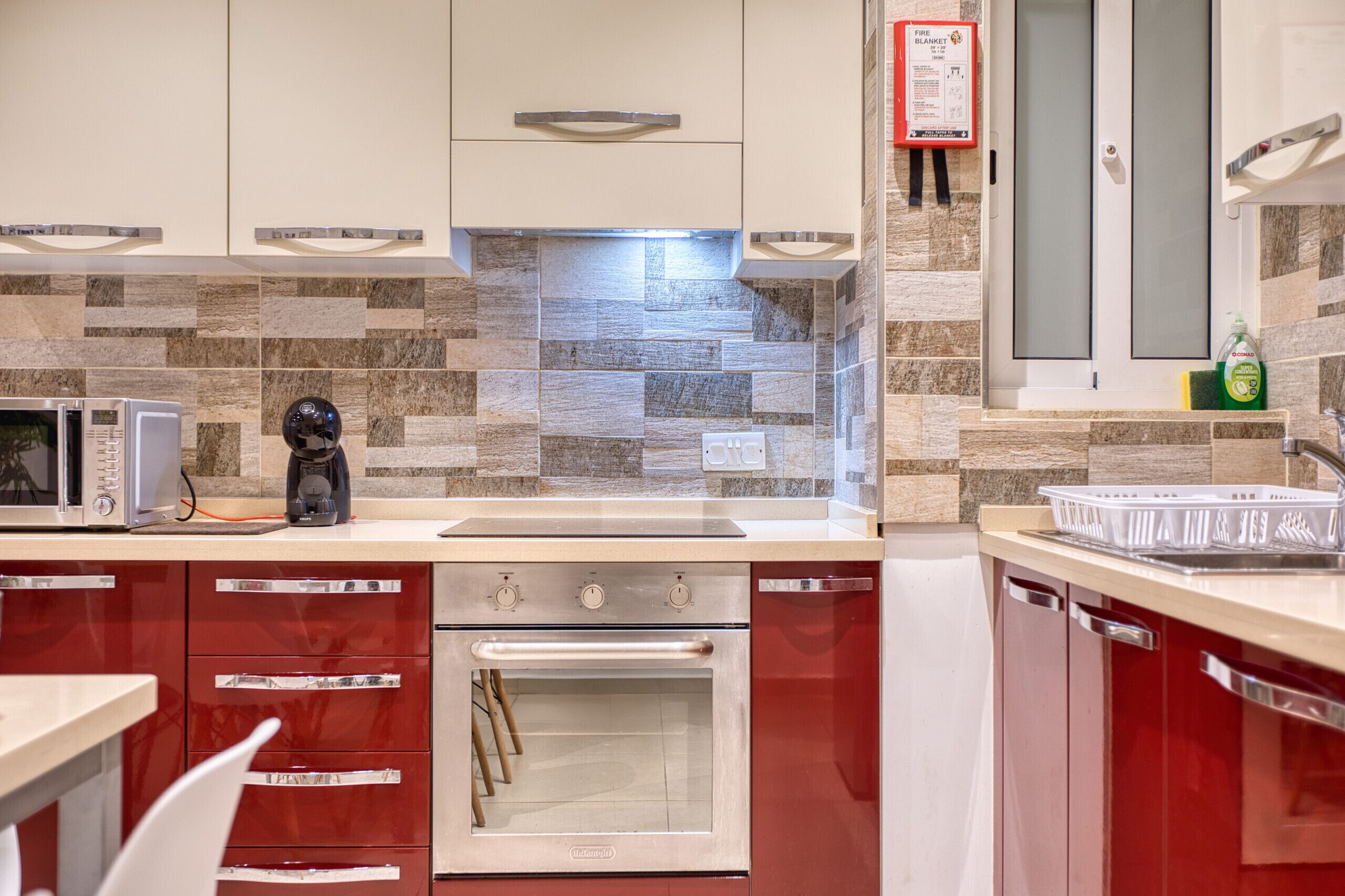 A modern kitchen with a microwave, coffee maker, oven, and a fire safety notice.