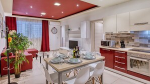 Una cocina moderna con comedor, detalles en rojo y una planta en maceta.