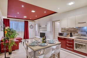 A modern kitchen with a dining area, red accents, and a potted plant. - Modern 2 bedroom flat with yard in Sliema NBOR1-1 (Sliema)