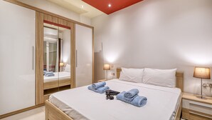 Una habitación de hotel con cama, armario, mesita de noche y lámpara.