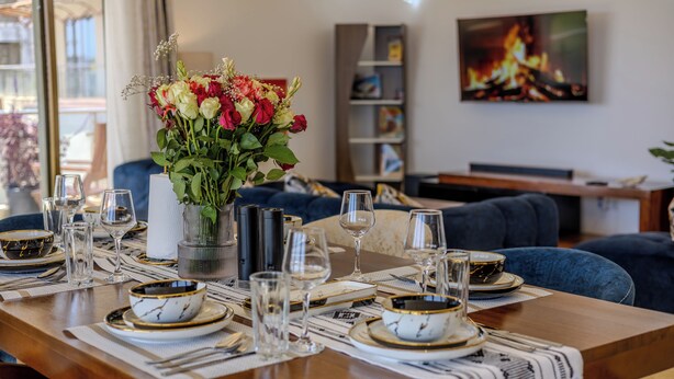 A dining table set with plates, glasses, and a vase of flowers. - 3-bedroom seaview apartment in Mombasa, close to the beach, with AC (Mombasa)