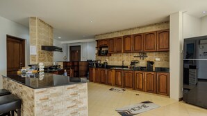 A modern kitchen with a central island, wooden cabinets, a built-in microwave, and a stainless steel refrigerator. - 3-bedroom seaview apartment in Mombasa, close to the beach, with AC (Mombasa)
