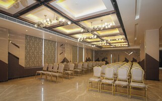 A conference room with rows of chairs, a high ceiling with lighting fixtures, and patterned wall panels.
