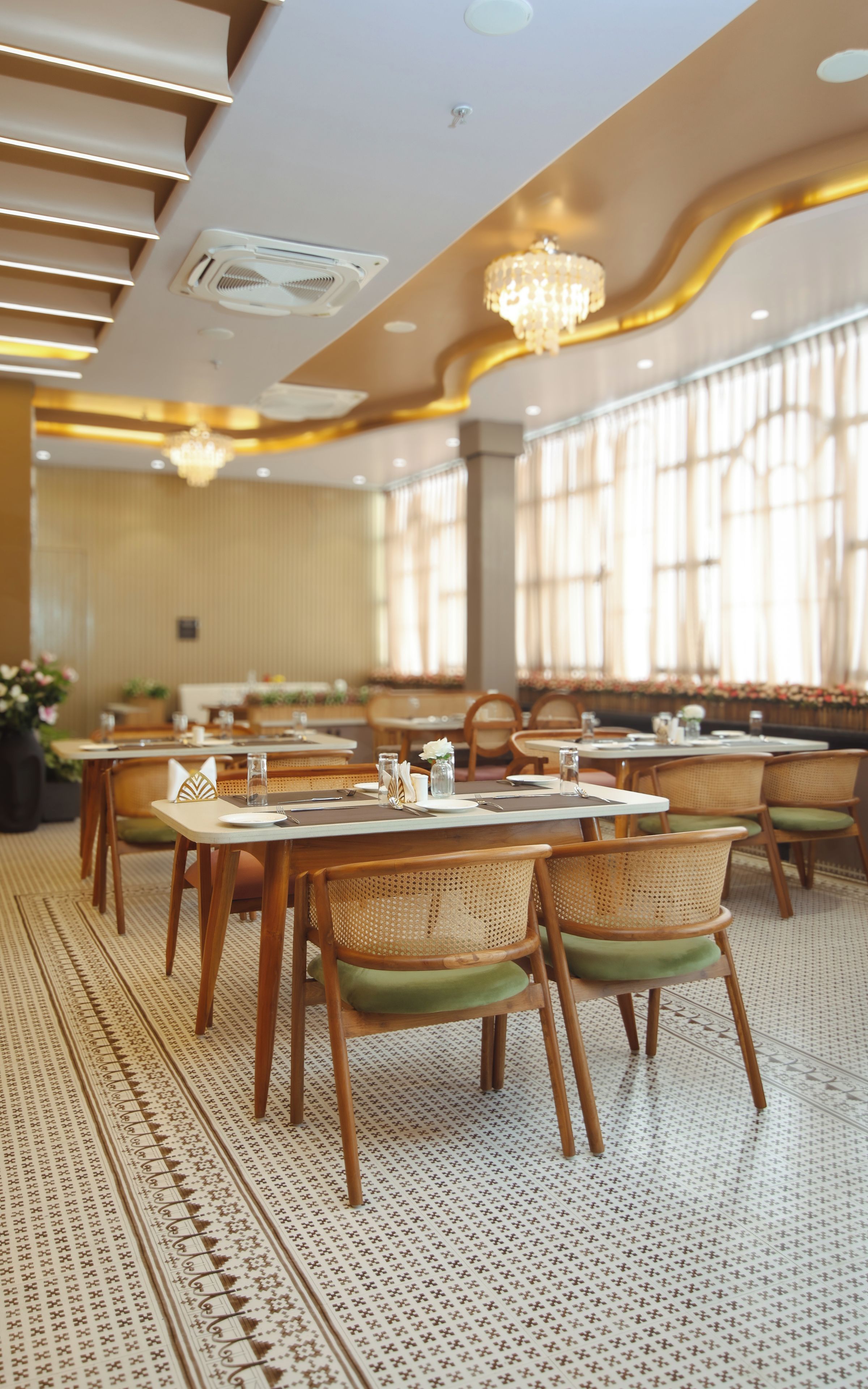 Un espace repas avec des tables et des chaises, une moquette à motifs et un lustre.