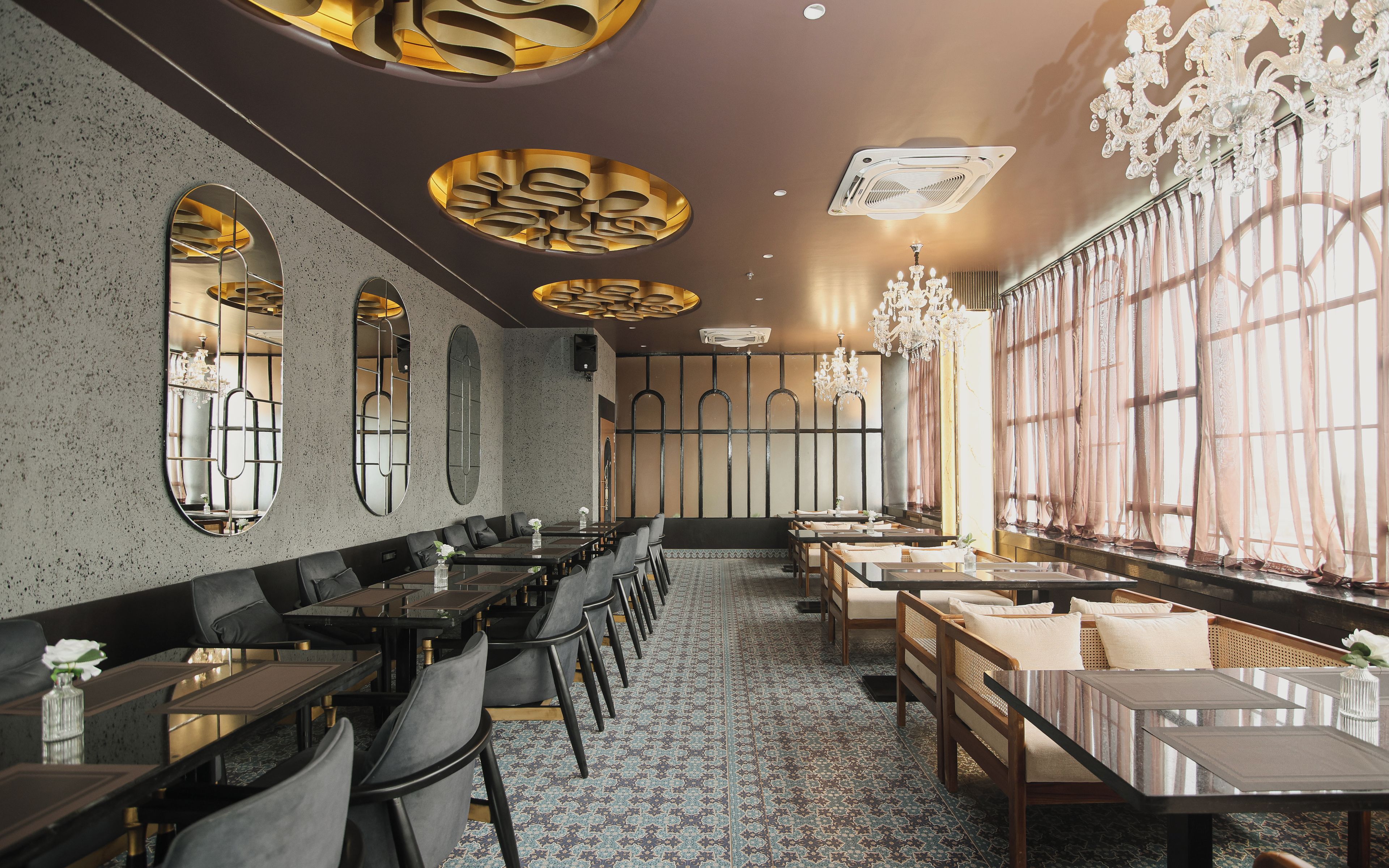 A restaurant interior with long tables, chairs, and a patterned floor.