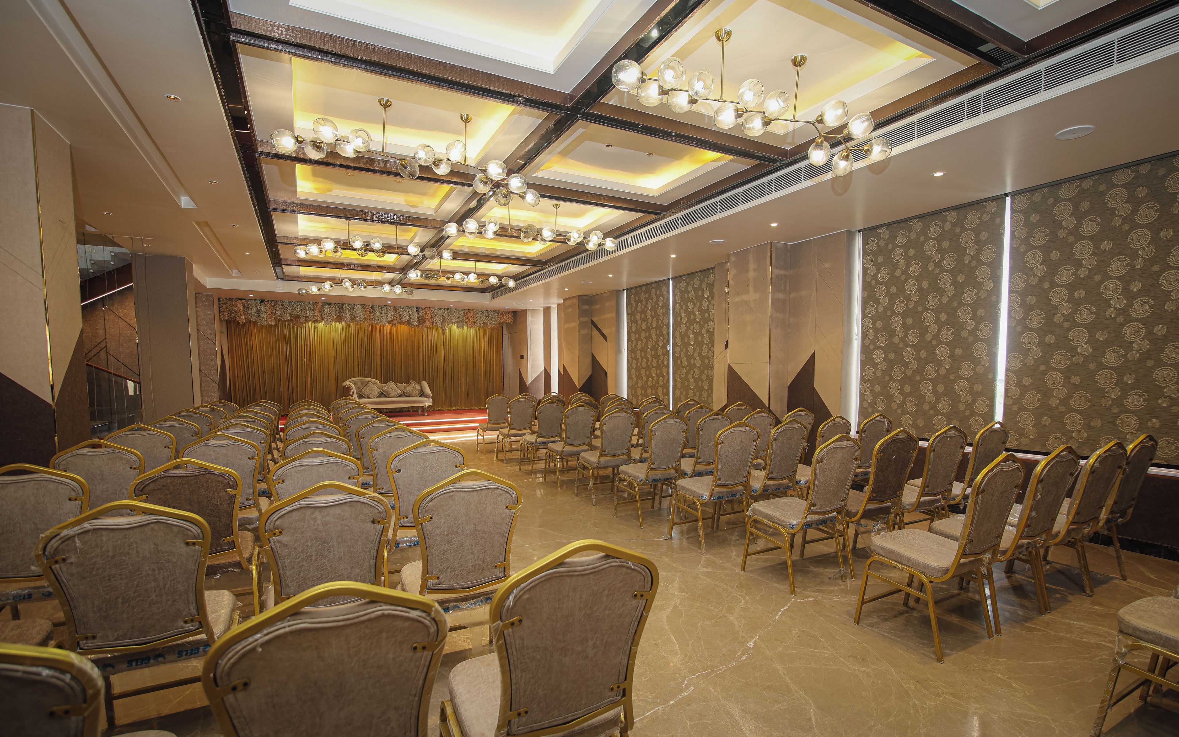 Uma sala de conferências com fileiras de cadeiras, um palco e uma parede com padrão.
