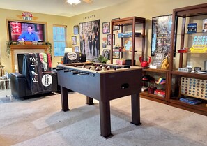 Una habitación con mesa de futbolín, televisor y fotomatón.