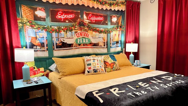 A hotel room with a bed, nightstands, a lamp, a TV, and a wall decorated with a Christmas theme. - “Friends” Central Perk- Fun Escape - Starved Rock- Ottawa (Ottawa)