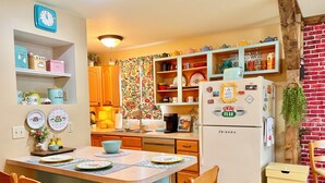 A kitchen with wooden cabinets, a central island with chairs, a refrigerator with magnets, and a brick wall. - “Friends” Central Perk- Fun Escape - Starved Rock- Ottawa (Ottawa)