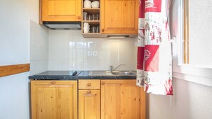 Una cocina compacta con gabinetes de madera, una encimera negra y un lavamanos de acero inoxidable.
