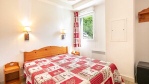 Un dormitorio con una cama de madera, dos lámparas de noche, un ventanal con cortinas y un radiador.