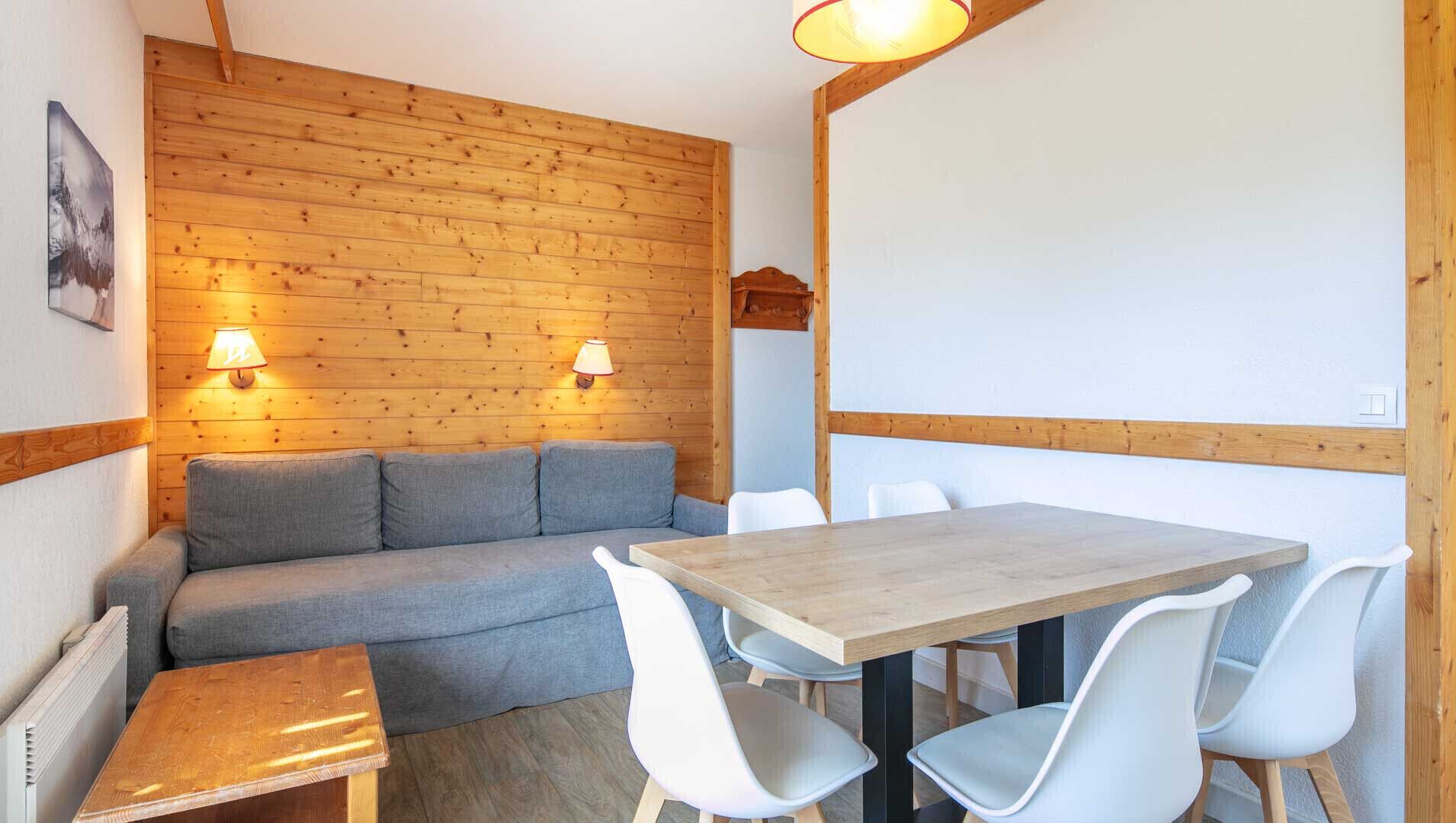 Una habitación acogedora con una pared de madera, un sofá, una mesa y sillas.