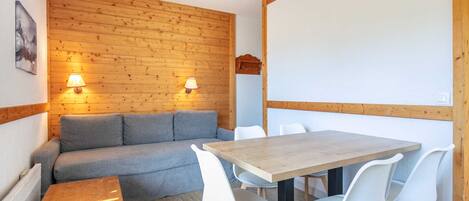 A cozy room with a wooden wall, a sofa, a table, and chairs.