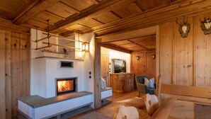 A wooden interior with a fireplace, seating area, and a view into another room. - Golmerhaus (Tschagguns)