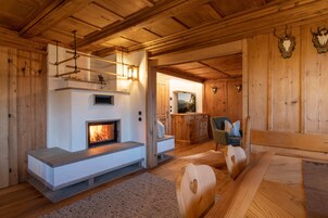 Interior de madera con chimenea, zona de estar y vista a otra habitación.