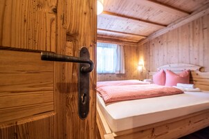Una habitación de cabaña de madera con una cama, un ventanal y una puerta con picaporte de metal.