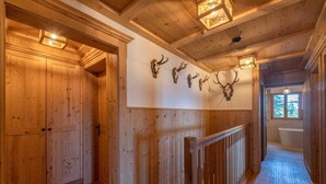 A wooden hallway with a wooden staircase, a white wall with mounted animal skulls, and a bathtub in the background. - Golmerhaus (Tschagguns)