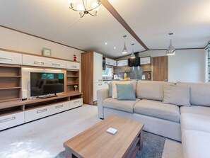 Ein modernes Wohnzimmer mit Flachbildfernseher, einer Holz-Unterhaltungseinrichtung, einem beigefarbenen Sofa und einem Couchtisch.