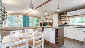 A modern kitchen with white cabinetry, a central island, and pendant lighting. - Fern View - Kelling Heath Holiday Park (Holt)