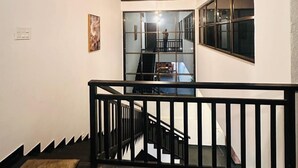 Uma escadaria com corrimão preto que leva a um patamar com uma janela grande.