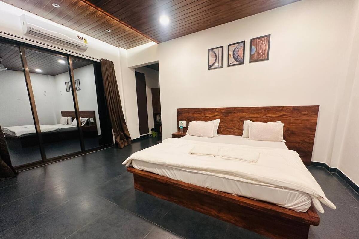 A modern hotel room with a large bed, a mirror, and artwork on the wall.