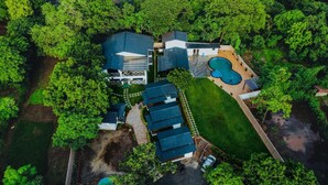 Vista aérea de uma propriedade com vários edifícios, piscina e vegetação ao redor.