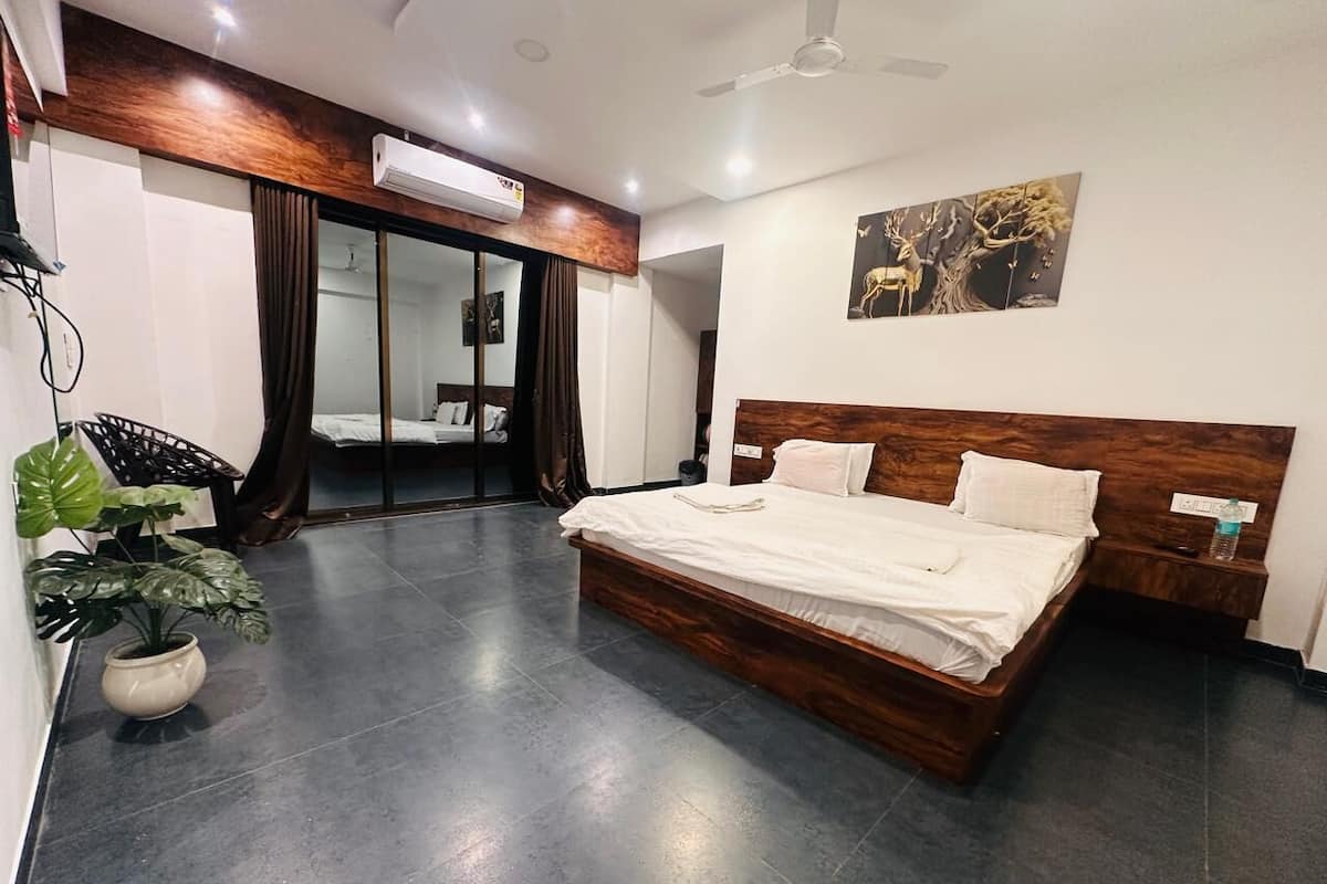 A modern hotel room with a large bed, a potted plant, a ceiling fan, and a wall-mounted air conditioner.