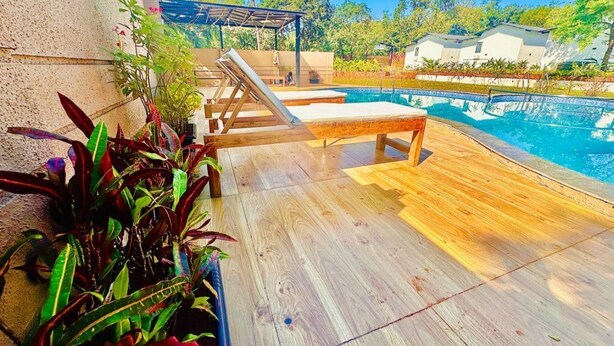 Um deck de madeira com cadeiras de descanso e uma piscina.