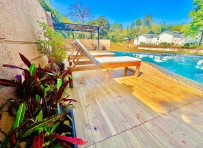 A wooden deck with lounge chairs, a pool, and potted plants. - Casa Mounterria (Alibag)