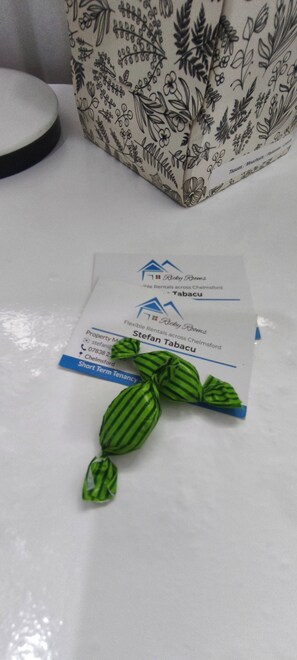 Tarjeta de presentación de una empresa de alquileres de propiedades, un pequeño adorno verde y una tela estampada de fondo.